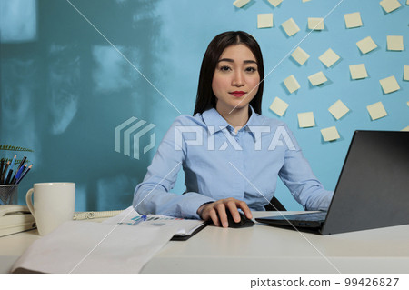 Professional business woman working on laptop while sitting in the office. Asian female employee working on notebook during daytime creating report for meeting with management. Professional business woman working on laptop while sitting in the office. Asian female employee working on notebook during daytime creating report for meeting with management. 99426827