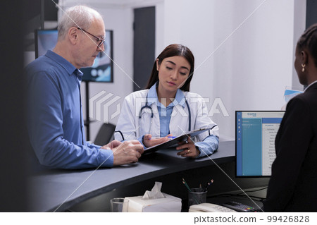 Physician showing disease diagnosis report to sick elderly patient discussing health care treatment in hospital waiting area. Medic prescribing medication to help manage the man chronic pain. Physician showing disease diagnosis report to sick elderly patient discussing health care treatment in hospital waiting area. Medic prescribing medication to help manage the man chronic pain. 99426828