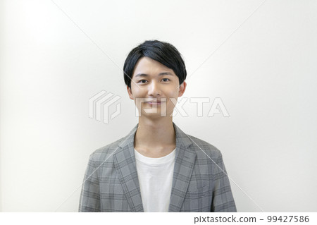 Portrait of a man in his early twenties smiling at the camera 99427586
