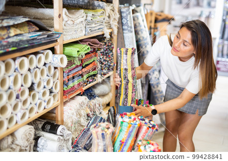 Woman choosing rug at household goods shop 99428841