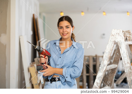 Portrait of smiling young woman with drill Portrait of smiling young woman with drill 99429004