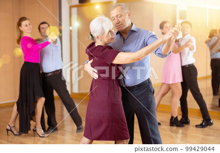 Elderly pair practicing ballroom dance in dance studio 99429044