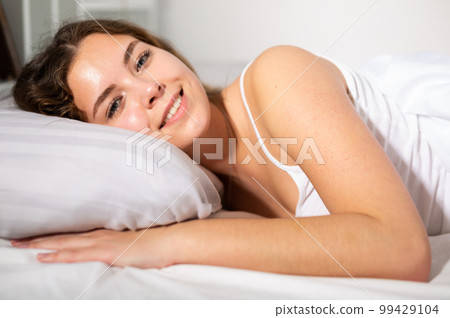 Young girl on white sheets in bed closeup 99429104