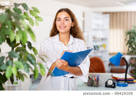 Friendly female administrative secretary writing down tasks in office 99429109