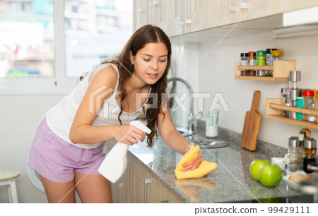 Friendly woman with rag cleaning kitchen at home 99429111