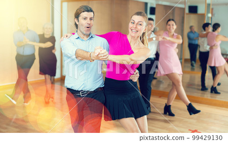 Middle-aged pair practicing Latino dance in dance studio Middle-aged pair practicing Latino dance in dance studio 99429130