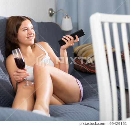 Happy young woman watching tv relaxing on sofa 99429161