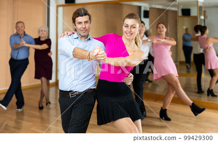Middle-aged pair practicing Latino dance in dance studio Middle-aged pair practicing Latino dance in dance studio 99429300
