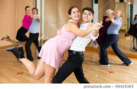 Cheerful young guy and girl practicing ballroom dances in ballroom Cheerful young guy and girl practicing ballroom dances in ballroom 99429365