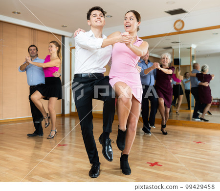 Young pair practicing Latino dance in dance studio Young pair practicing Latino dance in dance studio 99429458