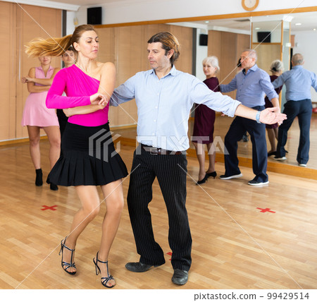 Adult couple practicing vigorous lindy hop in dance class Adult couple practicing vigorous lindy hop in dance class 99429514