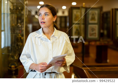 Young woman with information booklet visiting museum Young woman with information booklet visiting museum 99429522