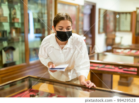 Woman exploring artworks in glass case in museum 99429528