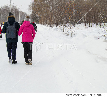 happy married couple walking in winter Park during snowfall 99429870