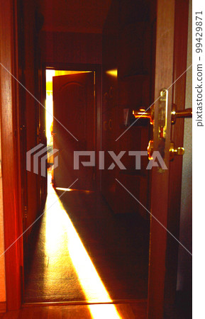 A beam of light falling on the floor through the open door in the room 99429871