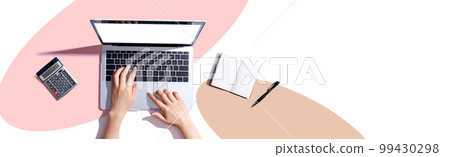 Person using a laptop computer with a notebook 99430298