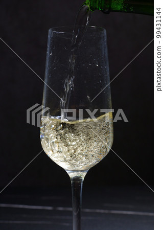 Pour well-chilled champagne (sparkling wine) into a flute glass Pour well-chilled champagne (sparkling wine) into a flute glass 99431144