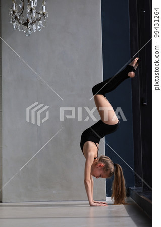 slim artistic teenage girl in black leotard training and leggings is training. rhythmic gymnastic exercise, children's professional sports 99431264