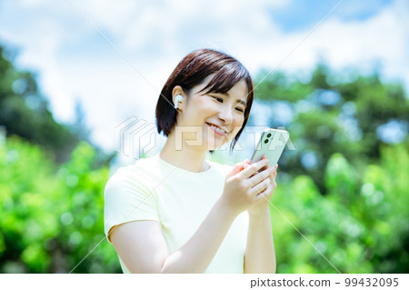 一個女人在新鮮的綠色中聽音樂 99432095