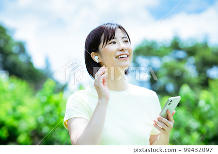 一個女人在新鮮的綠色中聽音樂 99432097