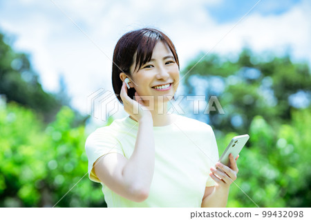 A woman listening to music in the fresh green 99432098