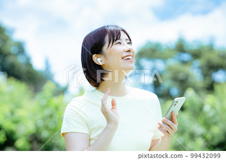 一個女人在新鮮的綠色中聽音樂 99432099
