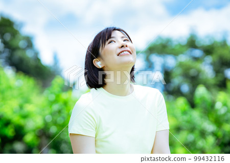 一個女人在新鮮的綠色中聽音樂 99432116