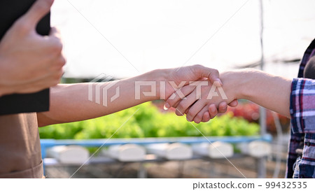 Close-up image of a successful farm owner shaking hand with a farmer or supplier, dealing business 99432535