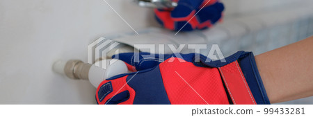 Plumber adjusts heating system in radiators of house 99433281