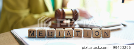 Mediator sitting near gavel of judge and words mediation closeup 99433296