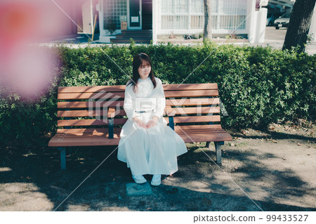 Photo of a young woman sitting on a bench Photo of a young woman sitting on a bench 99433527
