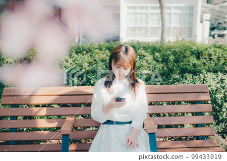 Photo of a young woman listening to music in the park 99433919