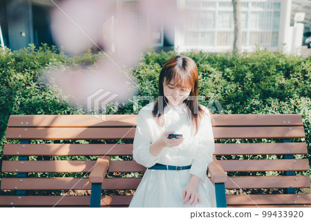 Photo of a young woman listening to music in the park 99433920