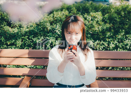 Photo of a young woman listening to music in the park 99433933