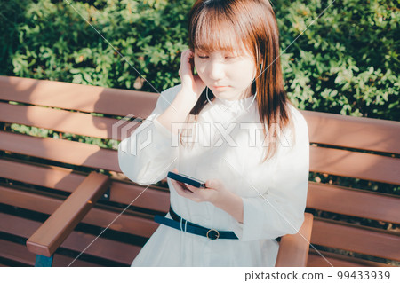 Photo of a young woman listening to music in the park 99433939