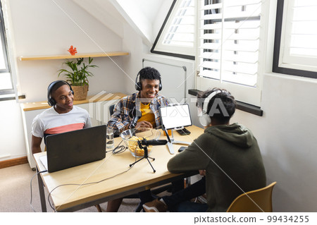 Image of happy diverse teenage boys with headphones and laptops at home Image of happy diverse teenage boys with headphones and laptops at home 99434255