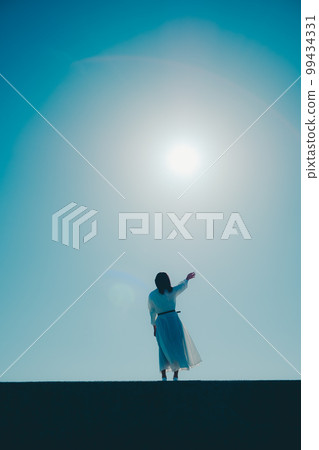 Photo of a young woman standing on the beach Photo of a young woman standing on the beach 99434331