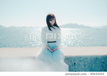 Photo of a young woman standing on the beach 99434445