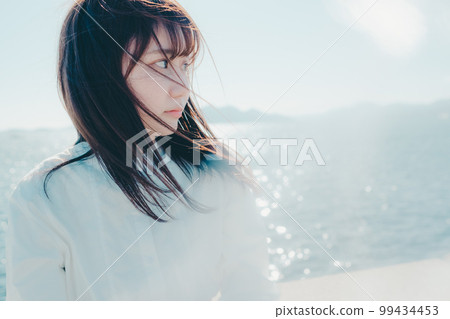 Photo of a young woman standing on the beach 99434453