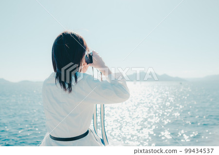 一位年輕女子在海灘上拿著相機的照片 99434537