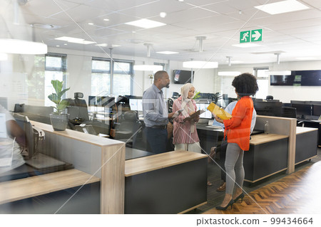 Happy diverse female and male businesspeople talking and working in office 99434664