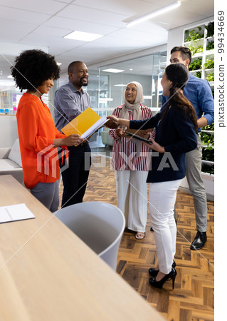 Vertical image of happy diverse female and male businesspeople talking and shaking hands in office Vertical image of happy diverse female and male businesspeople talking and shaking hands in office 99434669