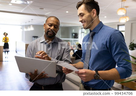 Image of diverse male colleagues working and talking in office 99434706