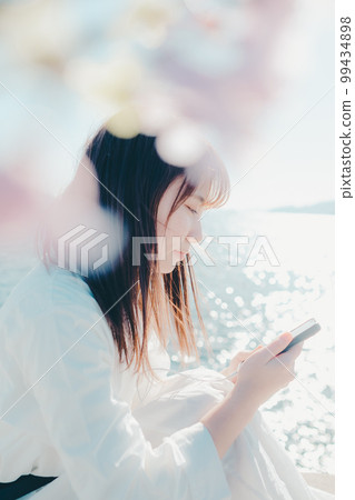 一位年輕女子在沙灘上聽音樂的照片 99434898