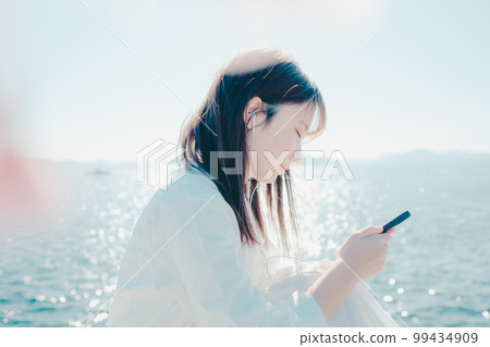 一位年輕女子在沙灘上聽音樂的照片 99434909