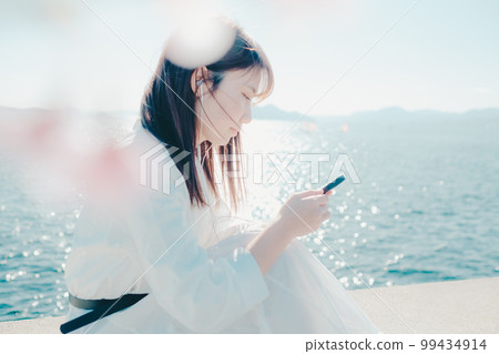 一位年輕女子在沙灘上聽音樂的照片 99434914