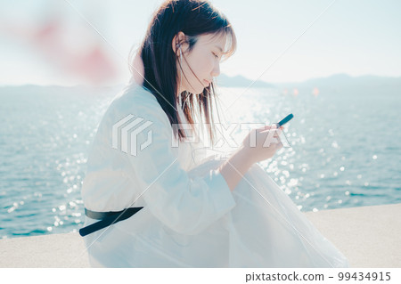 一位年輕女子在沙灘上聽音樂的照片 99434915