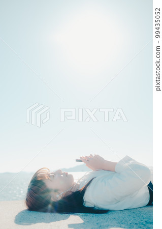 Photo of a young woman listening to music on the beach 99435052