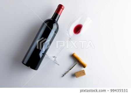 Bottle of red wine, glass and corkscrew on white background, with copy space 99435531