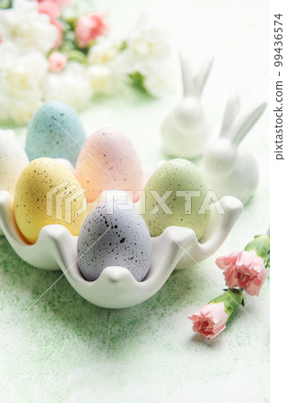 Easter decor. Colored Easter eggs on a ceramic stand and decorative rabbits. 99436574